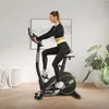 A woman is exercising on a stationary bike in a modern living room. Podgląd zdjęcia produktu