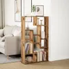 A wooden bookshelf with books and decorative items in a living room setting next to a sofa. Produktbild-Vorschau