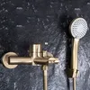 A close-up shot of a gold-colored shower faucet and handheld showerhead mounted on a dark, textured wall. Produktbild-Vorschau