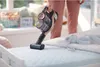 A person is using a cordless vacuum cleaner on a bed in a child's room. Produktbild-Vorschau