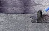 A roller is applying black sealant or coating to a textured surface. Produktbild-Vorschau