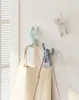 Three colorful wall hooks shaped like climbing figures are mounted on a white wall, with two tote bags hanging from two of the hooks. Náhled obrázku produktu