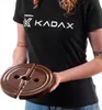 A person wearing a black t-shirt with a logo is holding a brown, circular object that is split into two halves. Anteprima dell’immagine prodotto