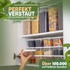 A person's hand is reaching for a clear food storage container filled with cookies, placed on a shelf in a kitchen cabinet filled with various food storage containers. Anteprima dell’immagine prodotto
