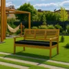 A wooden garden bench with a black cushion sits on a green lawn in a backyard setting. Produktbild-Vorschau