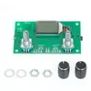 A green circuit board with an LCD screen, two potentiometers, and various electronic components, along with some loose hardware and two black knob caps, laid out on a white background. Náhled obrázku produktu