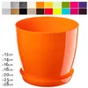 A single orange plastic plant pot with a matching saucer, shown against a white background. A grid of color swatches is visible at the top of the image, and a list of diameters is visible on the left. Podgląd zdjęcia produktu