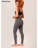 Frau trägt hoch taillierte graue Leggings und einen schwarzen Sport-BH, lächelt über die Schulter
