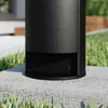 A close-up view of the base of a black outdoor lamp post, mounted on a concrete base, with grass in the foreground and background. Produktbild-Vorschau