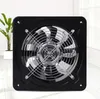 A black industrial axial fan with a silver grill is shown in a studio setting with a plant in the background. Voir les images du produit