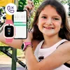 A young girl is smiling while holding onto a swing chain, with a smartwatch and a smartphone displayed in the foreground. Produktbild-Vorschau