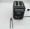 A black Tefal toaster with gold accents is shown on a white background. A pair of black tongs with gold tips is placed to the left of the toaster. Voir les images du produit