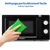A hand is cleaning the inside of a black microwave with a green sponge. Anteprima dell’immagine prodotto