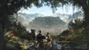 Two people in a boat are traveling down a river towards a large, ancient-looking city in the distance, surrounded by lush jungle and mountains. Podgląd zdjęcia produktu