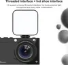 A black digital camera with a white light attachment on top, set against a white and gray background with abstract circular shapes. Podgląd zdjęcia produktu