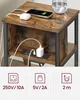 A close-up of a rustic brown bedside table with a black metal frame, featuring integrated charging ports. Náhled obrázku produktu