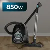 A black vacuum cleaner with a silver telescopic tube and a black hose is shown on a wooden floor, with some dirt on the floor near the vacuum head. A blue and white graphic overlay indicates '850w'. Produktbild-Vorschau
