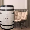 A wooden barrel-shaped cabinet and a chair are placed in a room with wooden walls. Produktbild-Vorschau