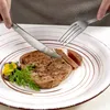 A person is cutting a piece of steak on a plate with a knife and fork. Produktbild-Vorschau