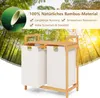 A bamboo laundry basket with two compartments is shown against a backdrop of a bamboo forest with sunlight filtering through. Anteprima dell’immagine prodotto