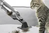 A hand vacuum cleaner is cleaning cat fur off a gray surface next to a tabby cat. Produktbild-Vorschau