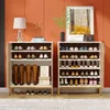 Two white and brown shoe cabinets are shown side-by-side against an orange wall. The cabinets are filled with shoes and boots. A lamp and decorative items are on top of the left cabinet, and a framed picture and plant are on top of the right cabinet. Anteprima dell’immagine prodotto