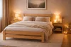 A bedroom scene with a wooden bed as the main focus, decorated with warm lighting and soft furnishings. Produktbild-Vorschau