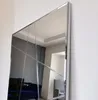 A large mirror with a silver frame is mounted on a white wall. Náhled obrázku produktu