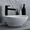 A modern bathroom sink with a black faucet and decorative vases in the background. Náhľad obrázku produktu
