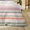 A close-up view of a striped duvet cover with a light-colored sheet draped over it, resting on a wooden floor. Produktbild-Vorschau