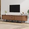 A TV lowboard with decorative vases and a plant on top, placed in a living room setting with a rug and a wall-mounted TV. Podgląd zdjęcia produktu