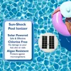 A person is floating on a pink inflatable ring in a swimming pool, next to a solar pool ionizer. Produktbild-Vorschau