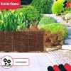A garden fence made of woven branches is shown in a garden setting with lush green plants and stone steps. Anteprima dell’immagine prodotto