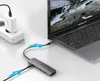 A UGREEN USB-C hub is connected to a MacBook Pro, with a power adapter plugged into a wall socket. Produktbild-Vorschau