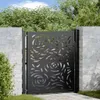 A black metal garden gate with a decorative floral pattern, set between two brick pillars, with greenery and sky in the background. Náhled obrázku produktu