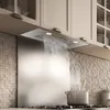 A modern kitchen range hood with steam rising from a pot on the stove below. Voir les images du produit