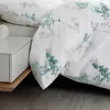 A close-up view of a duvet cover with a floral pattern, placed on a bed next to a nightstand. Produktbild-Vorschau