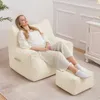 A woman relaxing on a beige beanbag chair with an ottoman in a well-lit room. Náhled obrázku produktu