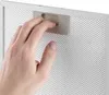 A hand is shown inserting a metal mesh filter into a white frame. Podgląd zdjęcia produktu