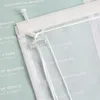 A close-up view of the top mechanism and hanging cords of a transparent blind with text printed on it. Produktbild-Vorschau
