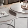 A close-up view of two round coffee tables, one nested inside the other, with a book on the lower table and a decorative tray with a glass on the upper table. Voir les images du produit