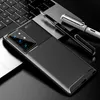A smartphone case with a carbon fiber texture is placed on a laptop keyboard, with two pens nearby. Produktbild-Vorschau