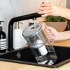 A person is filling a water filter pitcher under a faucet in a kitchen sink. Náhled obrázku produktu