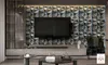 A modern living room with a TV mounted on a textured wall, a media console, and coffee tables. Produktbild-Vorschau