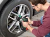 A man is using a cordless impact wrench to tighten the lug nuts on a car wheel. Náhľad obrázku produktu