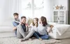A family is sitting on the floor in a living room, laughing and interacting. Produktbild-Vorschau