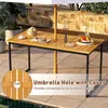 An outdoor table with food and drinks, set on a patio with plants and a stone wall in the background. Produktbild-Vorschau