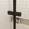 A close-up view of a shower door hinge and frame, with tiled walls and a shelf with toiletries in the background. Produktbild-Vorschau