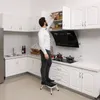 A man is reaching into a kitchen cabinet while standing on a step stool. Anteprima dell’immagine prodotto