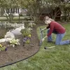 A woman is installing garden edging around a flower bed next to a pond. Podgląd zdjęcia produktu
